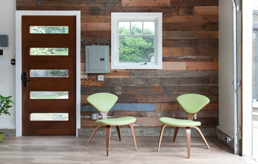Converted garage entry with wood plank wall and green chairs